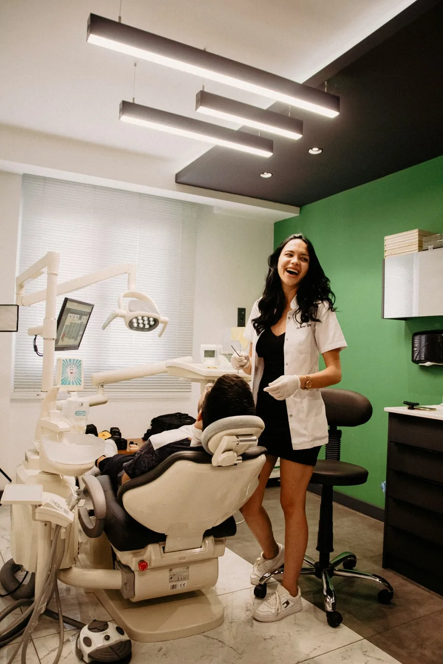 Smiling dentist beside a patient in a dental treatment room